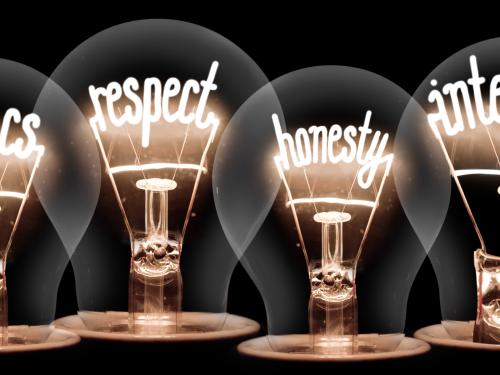 Row of four lightbulbs illuminating the words 'ethics', 'respect', 'honesty' and 'integrity' inside each one