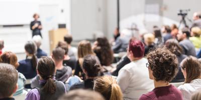 Students gathered for lecture; in background, standing lecturer