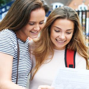 Two female student are reading a piece of paper with their exam results