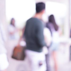 Blurred photo of a number of people in the middle distance, suggestive of movement and gathering together