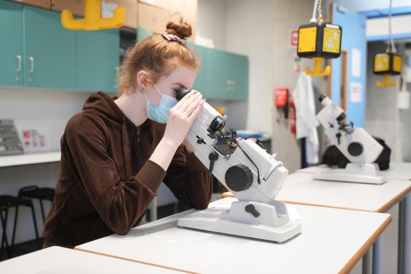 Female TU Dublin student looking into microscope in laboratory