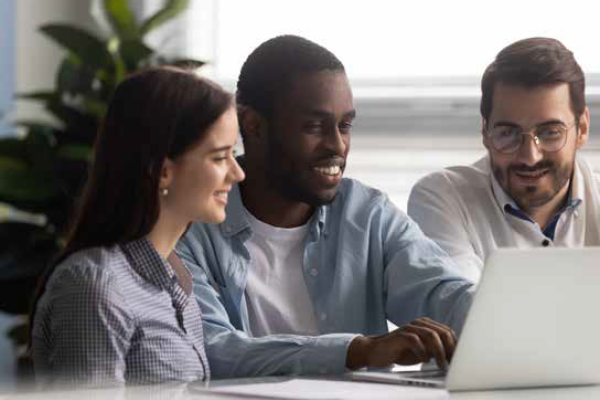 Stock photo showing three happy students of diverse background together looking at a laptop