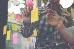 Two people reading post-it notes stuck to a window